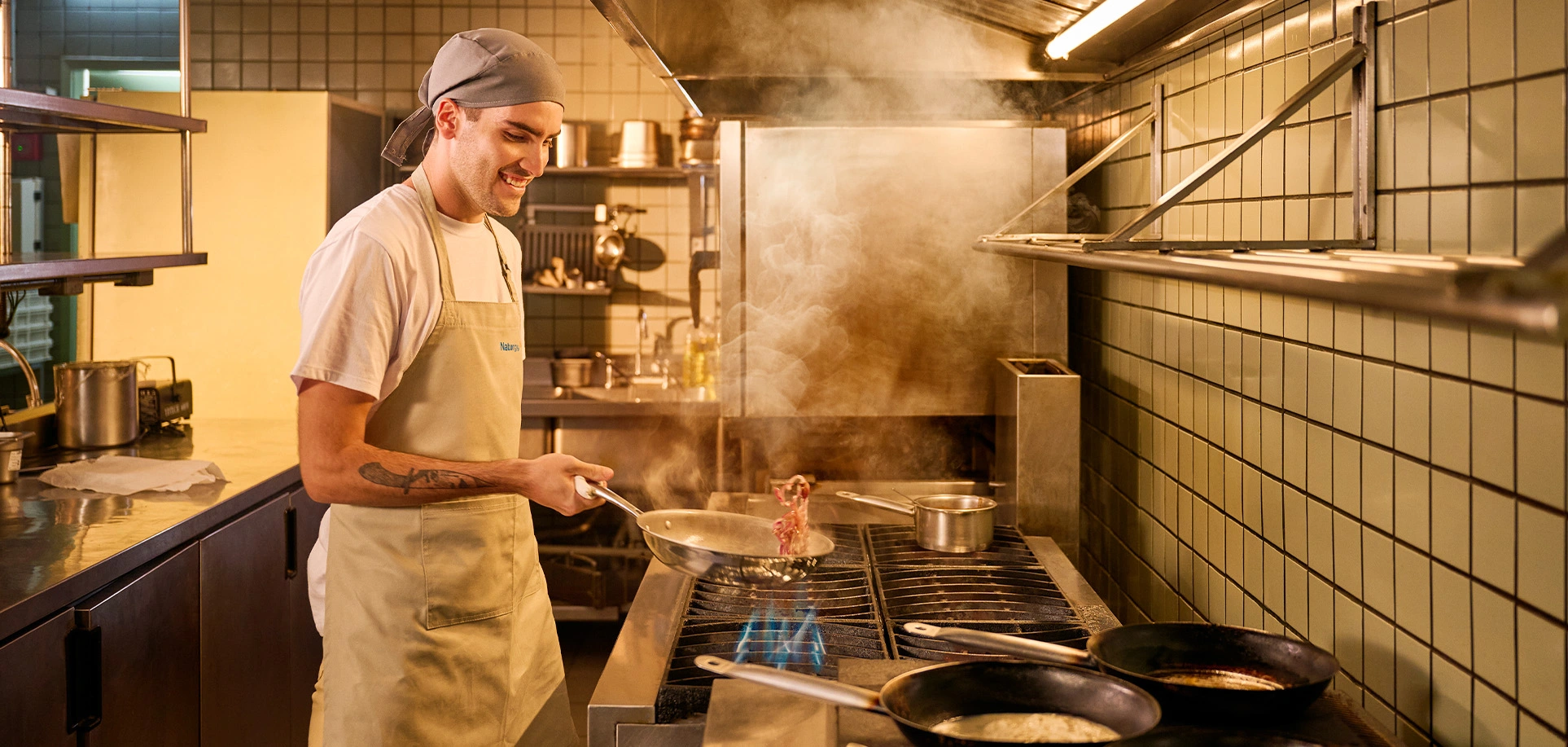 Cozinha em frente a um fogão usanda uma frigideira.